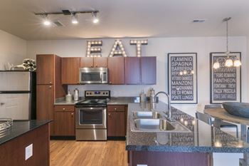 A modern kitchen with a large island and a stainless steel stove.